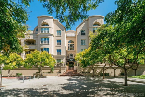 Front view of a multi-story residential building with arched windows and balconies.