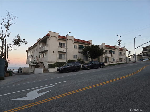 Front view of a multi-story apartment building on a sloped street.