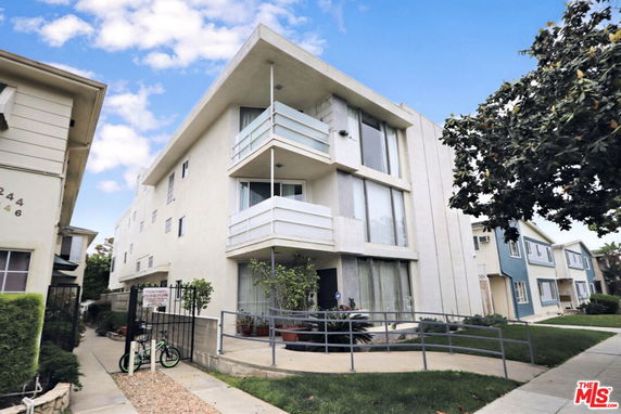 Front view of a multi-story apartment building with balconies and large windows.