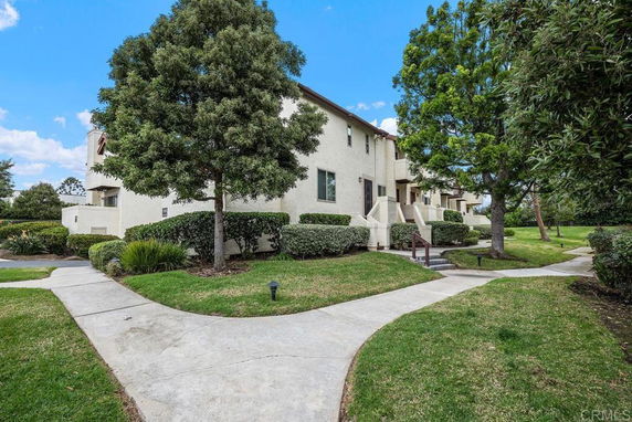 Front view of a multi-story residential building with a walkway and landscaped surroundings.