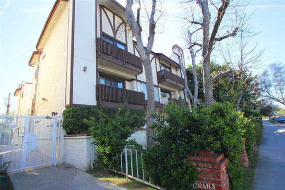 Front view of a multi-story residential building with balconies and gated entrance.