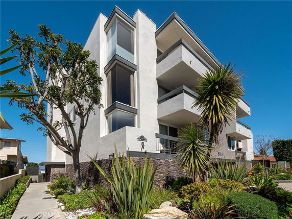 Front view of a modern multi-story building with balconies and large windows.