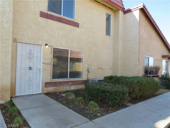 Front view of a two-story house with a metal security door and small windows.