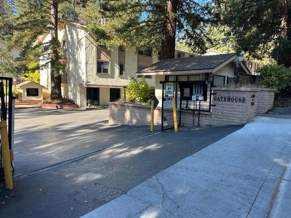 Front view of a building with a gatehouse and a driveway entrance.