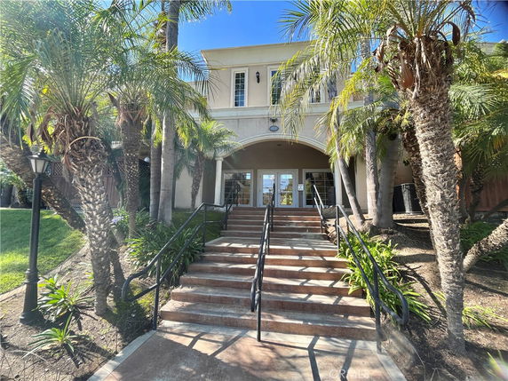 Front view of a two-story building with an arched entrance and steps leading up to it.