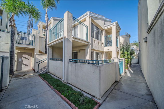 Front view of a multi-story house with balconies and a walkway.