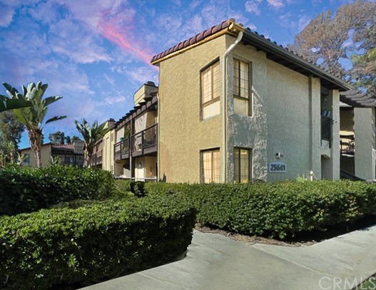 Front view of a multi-story residential building with beige exterior and balcony.