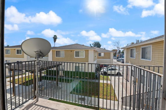 View from a balcony overlooking a courtyard with adjacent two-story residential buildings.