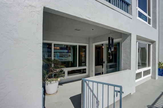 Front view of a residential building with large windows and a small gated patio area.