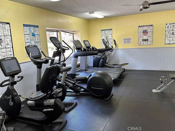 Indoor gym area with exercise equipment and workout posters on the walls.