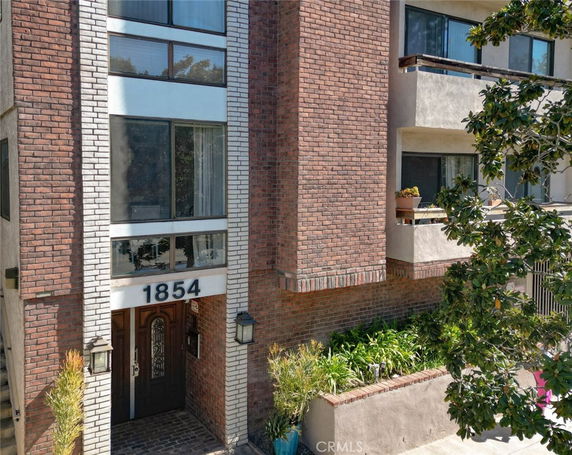 Front view of a multi-story brick and stucco building with balconies.