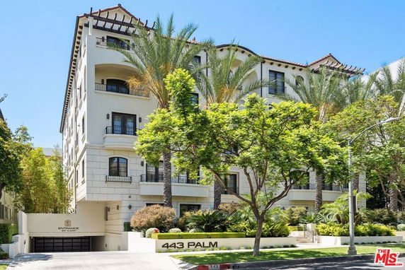 Front view of a multi-story residential building with palm trees in the foreground.