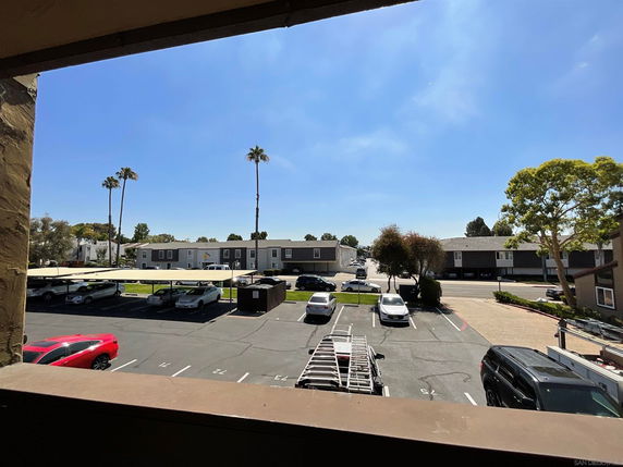 Outdoor parking area with several cars and covered parking spaces.