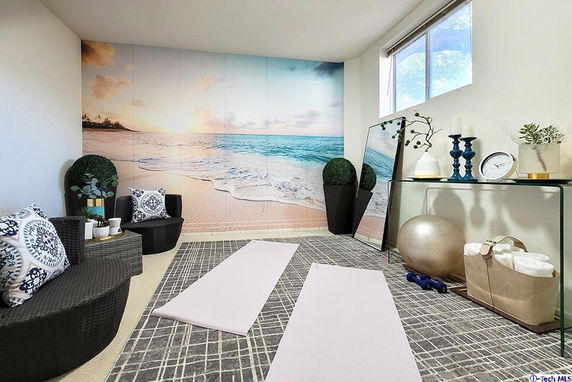 Interior view of a small room set up for yoga or relaxation with a beach mural on the wall.