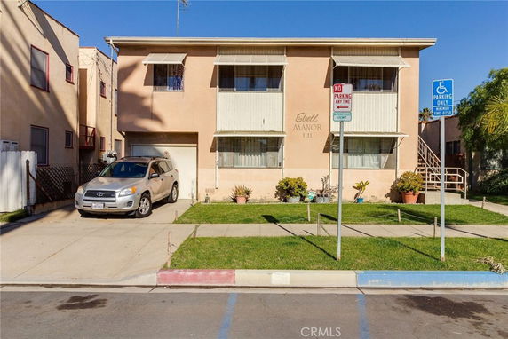 Front view of a two-story apartment building with a driveway and a car parked.