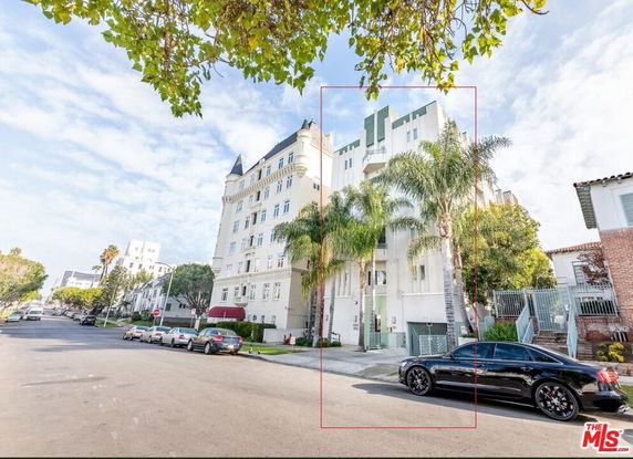 Front view of a multi-story residential building with palm trees.