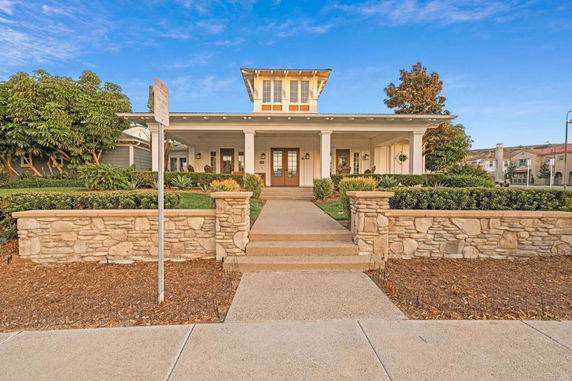 Front view of a house with a small upper structure and a stone boundary wall.