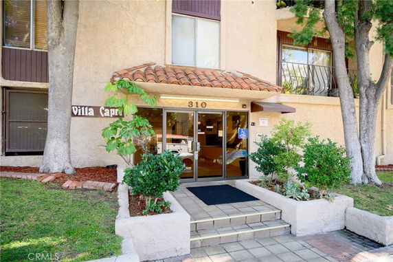 Front view of a multi-story building entrance with a tiled roof and glass doors.