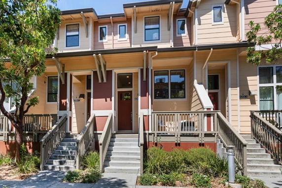 Front view of a multi-story townhouse with stairs leading to the entrance.