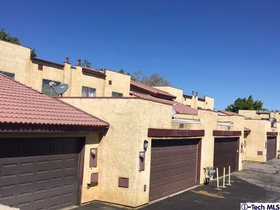 Front view of townhouses with attached garages and tiled roofs.
