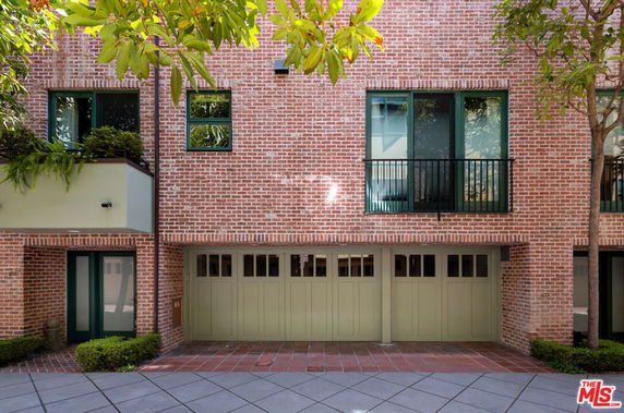 Front view of a brick house with green framed windows and a garage.
