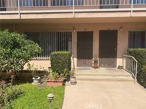 Front view of a two-story apartment building with doors and small garden area.