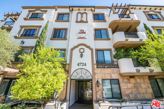 Front view of a multi-story apartment building with balconies and decorative elements.