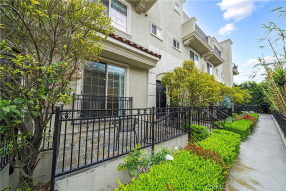 Front view of a multi-story residential building with balconies and decorative railings.