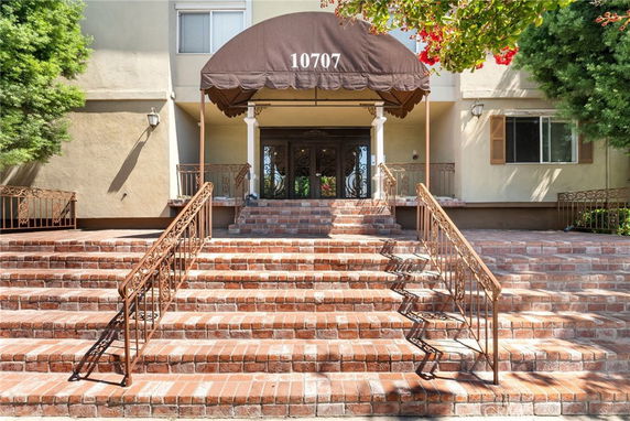 Front view of a building entrance with brick steps and an awning.