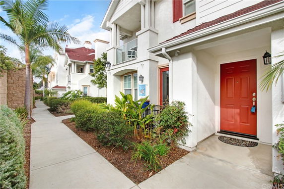 Front view of a multi-story house with a red door and a small garden area.