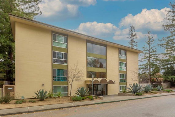 Front view of a multi-story residential building with large windows and an entrance canopy.