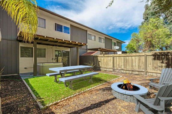 View of a backyard with a patio cover and fire pit.