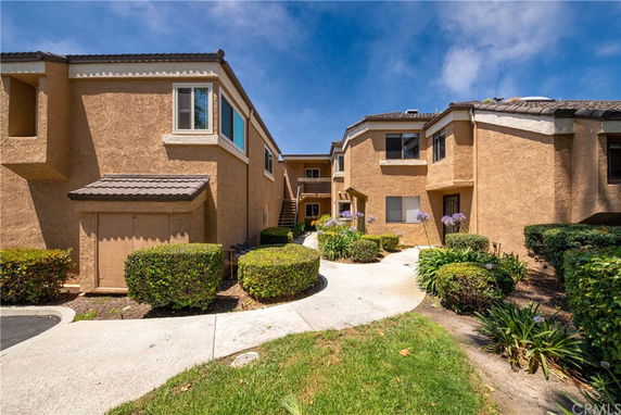 Front view of a multi-story residential building with a walkway and landscaped entrance.