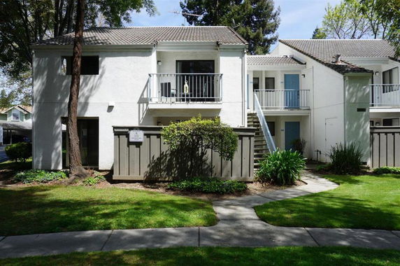 Front view of a two-story residential building with a small balcony and an external staircase.