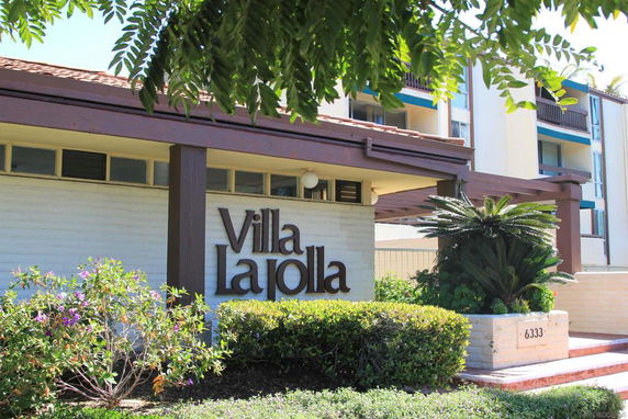 Front view of a multi-story building named Villa La Jolla with balconies and greenery.