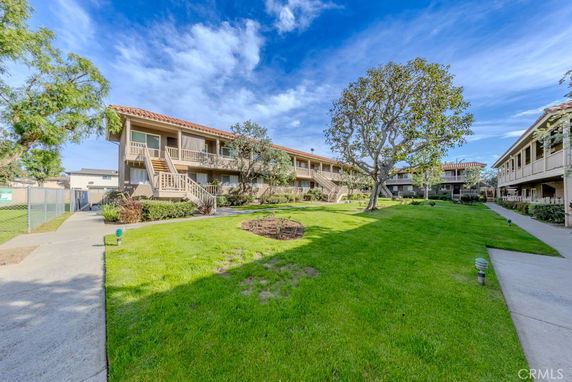 Front view of two-story apartment buildings with balconies and landscaped grounds.