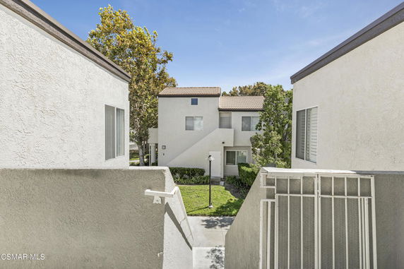 View of white buildings with trees and a pathway in a residential area.
