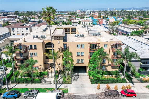 Front view of a multi-story apartment building with balconies and a gated entrance.
