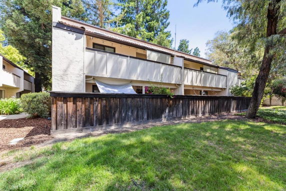 Front view of a two-story building with balconies and wooden fencing.