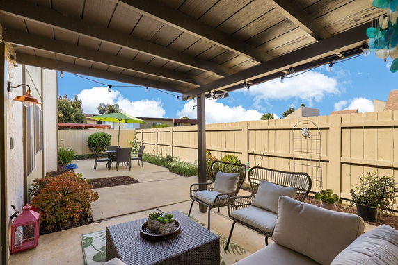 Outdoor patio area with seating, a table with an umbrella, and fenced yard.