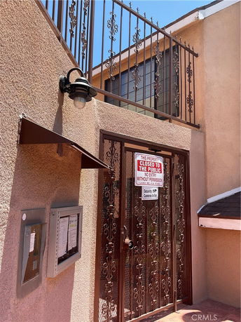 Front view of a building entrance with a decorative metal gate and signs.