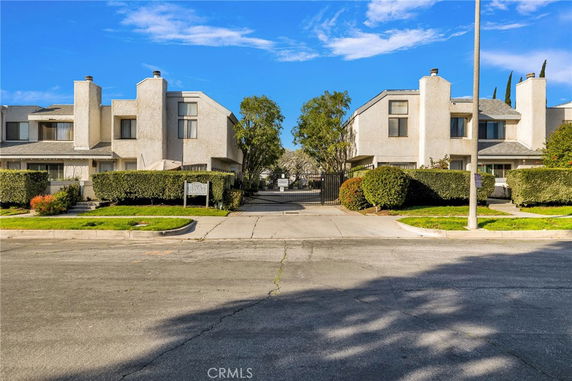 Front view of a residential building with two joined sections and gated entrance.