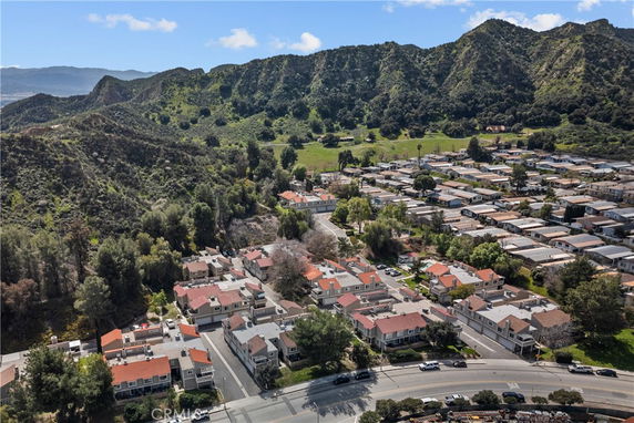 Aerial view of a residential area surrounded by mountains and greenery.