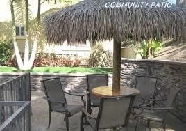 Outdoor patio area with thatched umbrella and several chairs around a table.