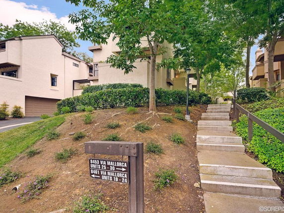 Front view of a multi-story apartment complex with units and a stairway leading up to entrances.