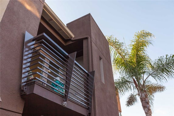 Front view of a modern house with a balcony featuring metal railing.