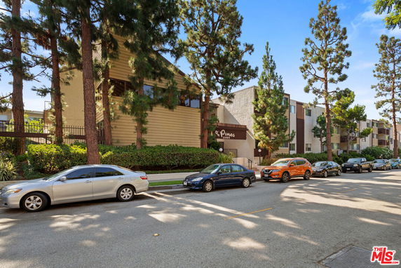 Front view of a multi-story residential building with trees lining the street.