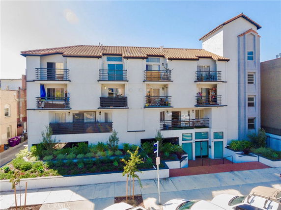 Front view of a multi-story building with balconies and a tiled roof.