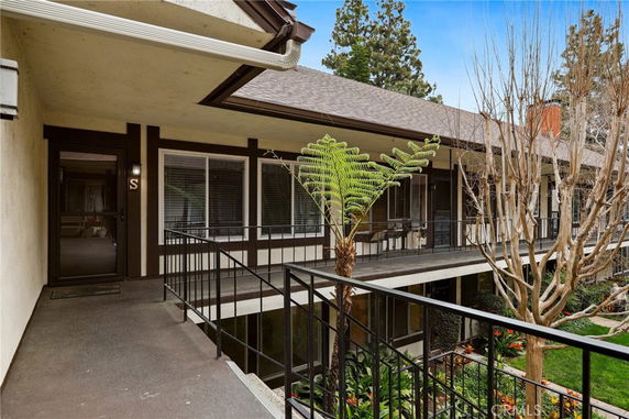 Front view of a two-story residential building with balconies and plants.