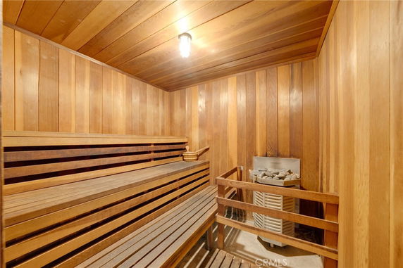 Wooden sauna room with benches and a heater.